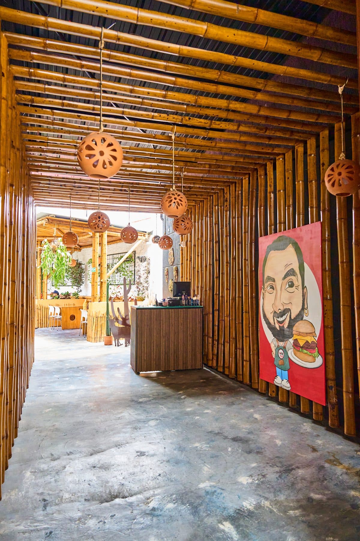 Pasillo de bambú con mural del chef y lámparas de barro